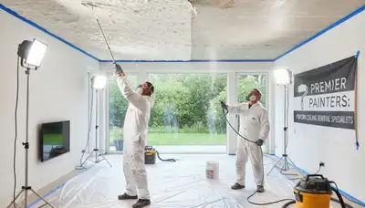 Technician removing popcorn ceiling in Loveland, CO home with professional dust-free painting service